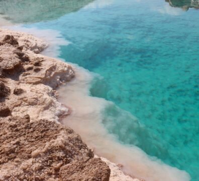 Stunning view of a turquoise salt lake surrounded by rocky desert terrain, a natural marvel.